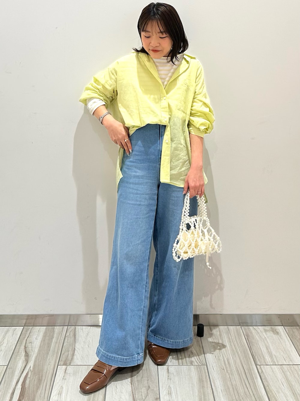 イエロー系のシャツ/ブラウス、ブラウン系のローファーを着用したレディースの夏コーディネートの2枚目の写真