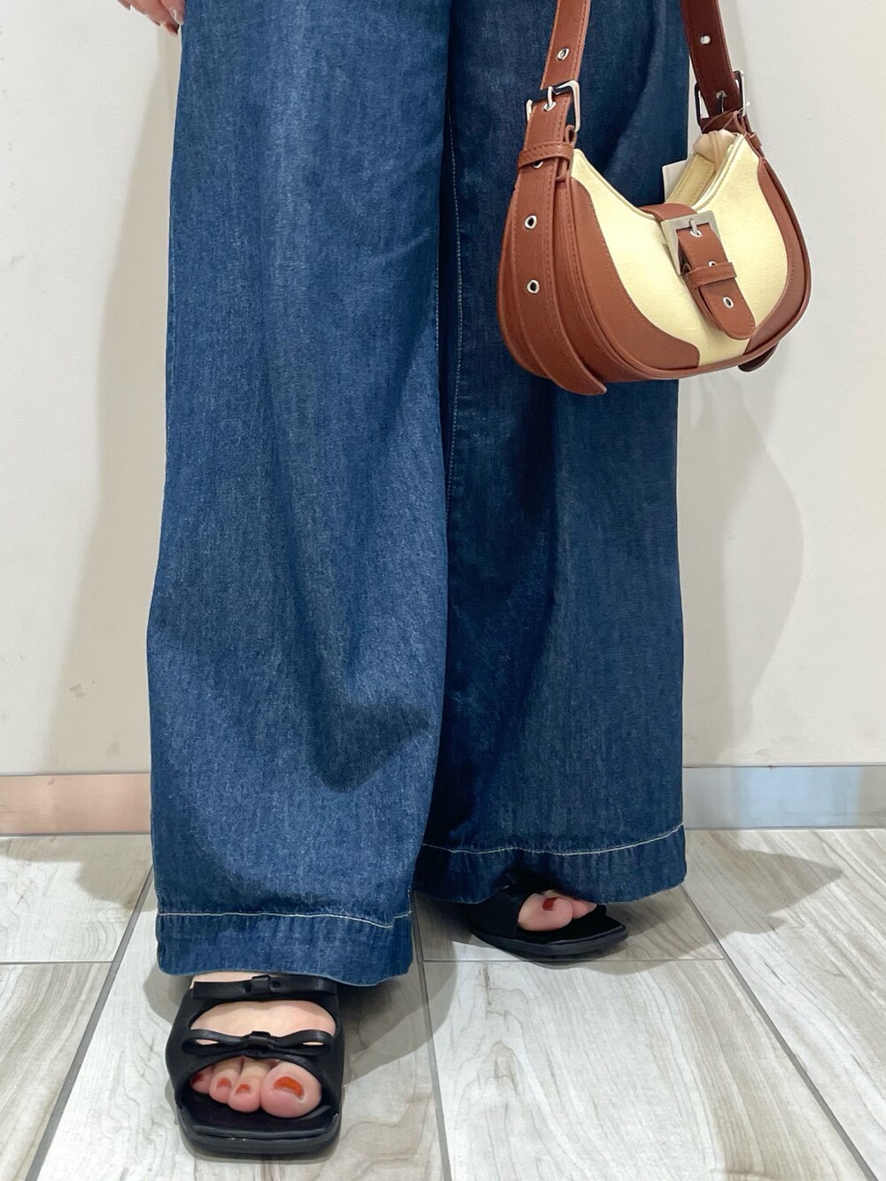 ブルー系のデニムパンツ、ブラウン系のショルダーバッグ、ホワイト系のカーディガン/ボレロを着用したレディースの春コーディネートの4枚目の写真