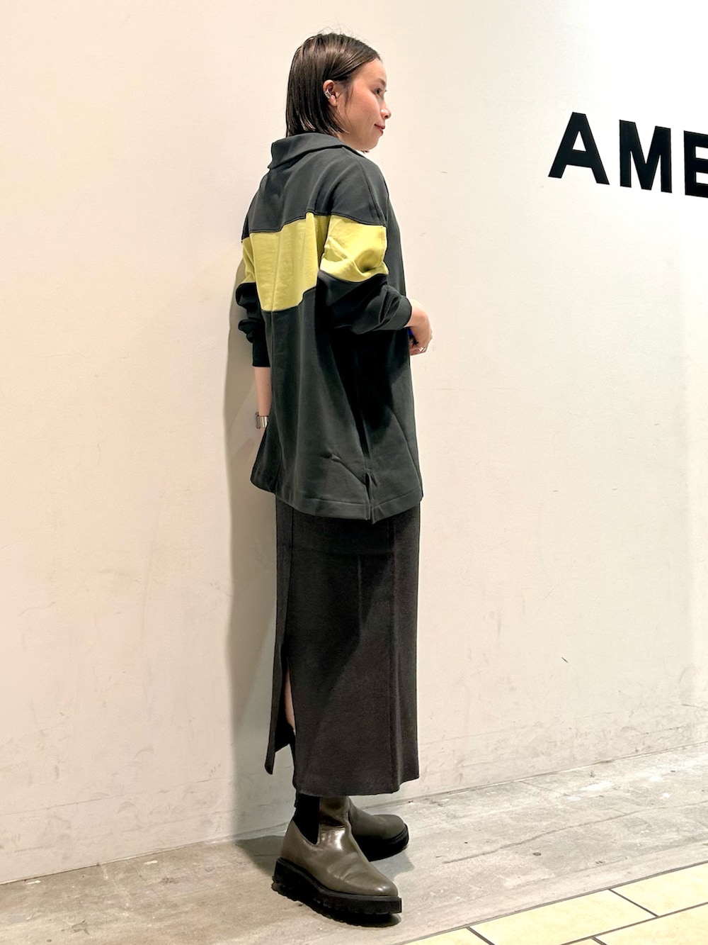 グリーン系のチュニック、グレー系のスカートを着用したレディースの秋コーディネートの2枚目の写真