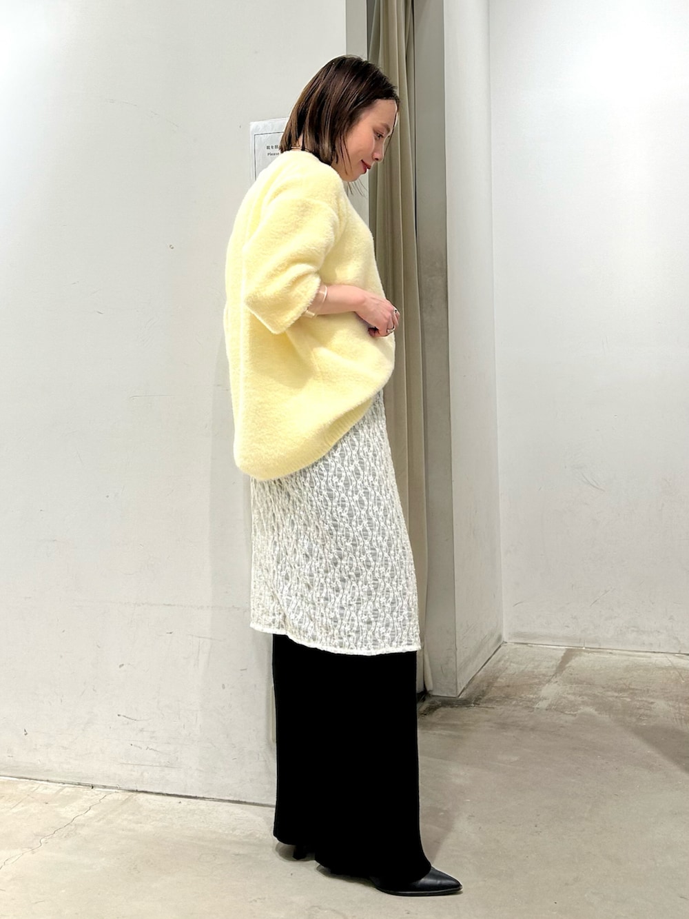 イエロー系のニット/セーター、ホワイト系のスカート、ブラック系のその他パンツを着用したレディースの冬コーディネートの2枚目の写真