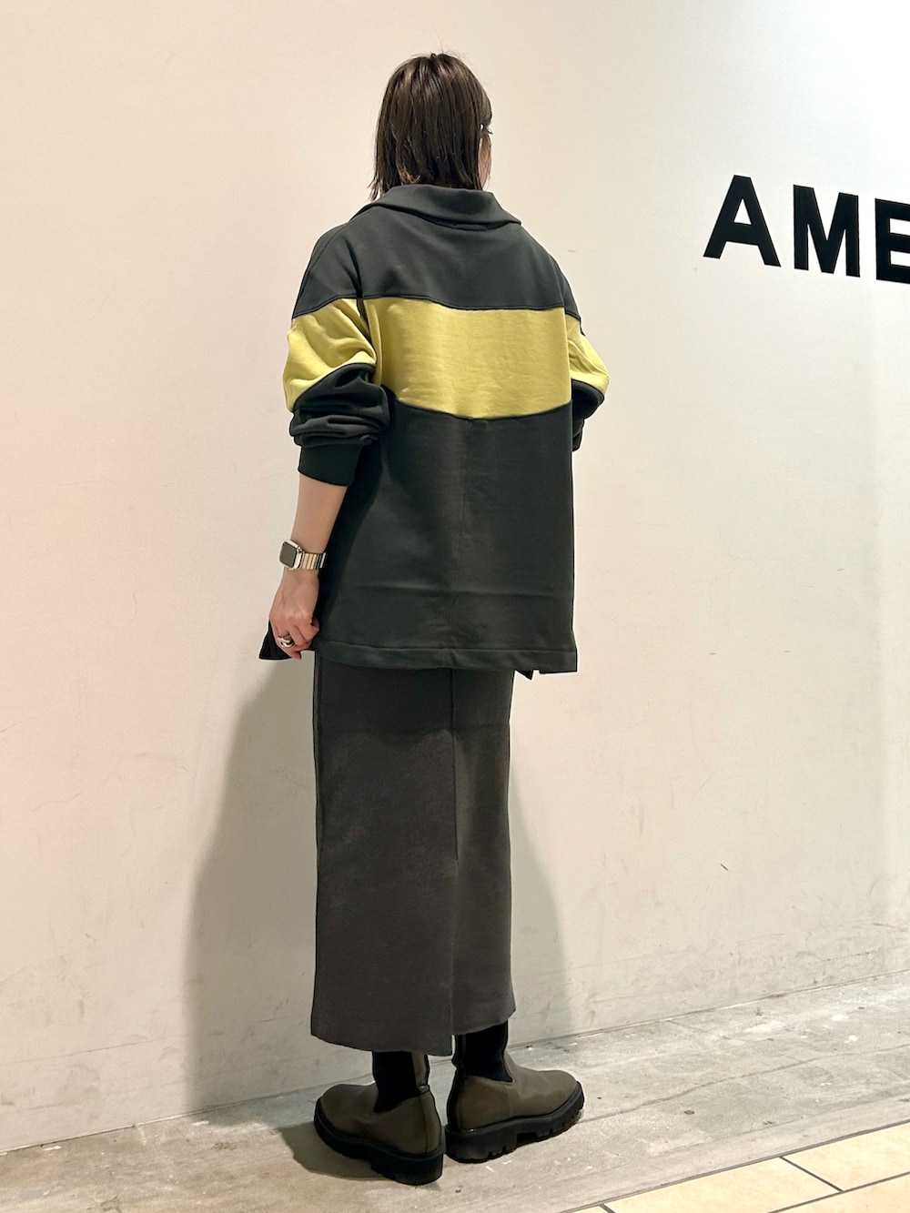 グリーン系のチュニック、グレー系のスカートを着用したレディースの秋コーディネートの3枚目の写真