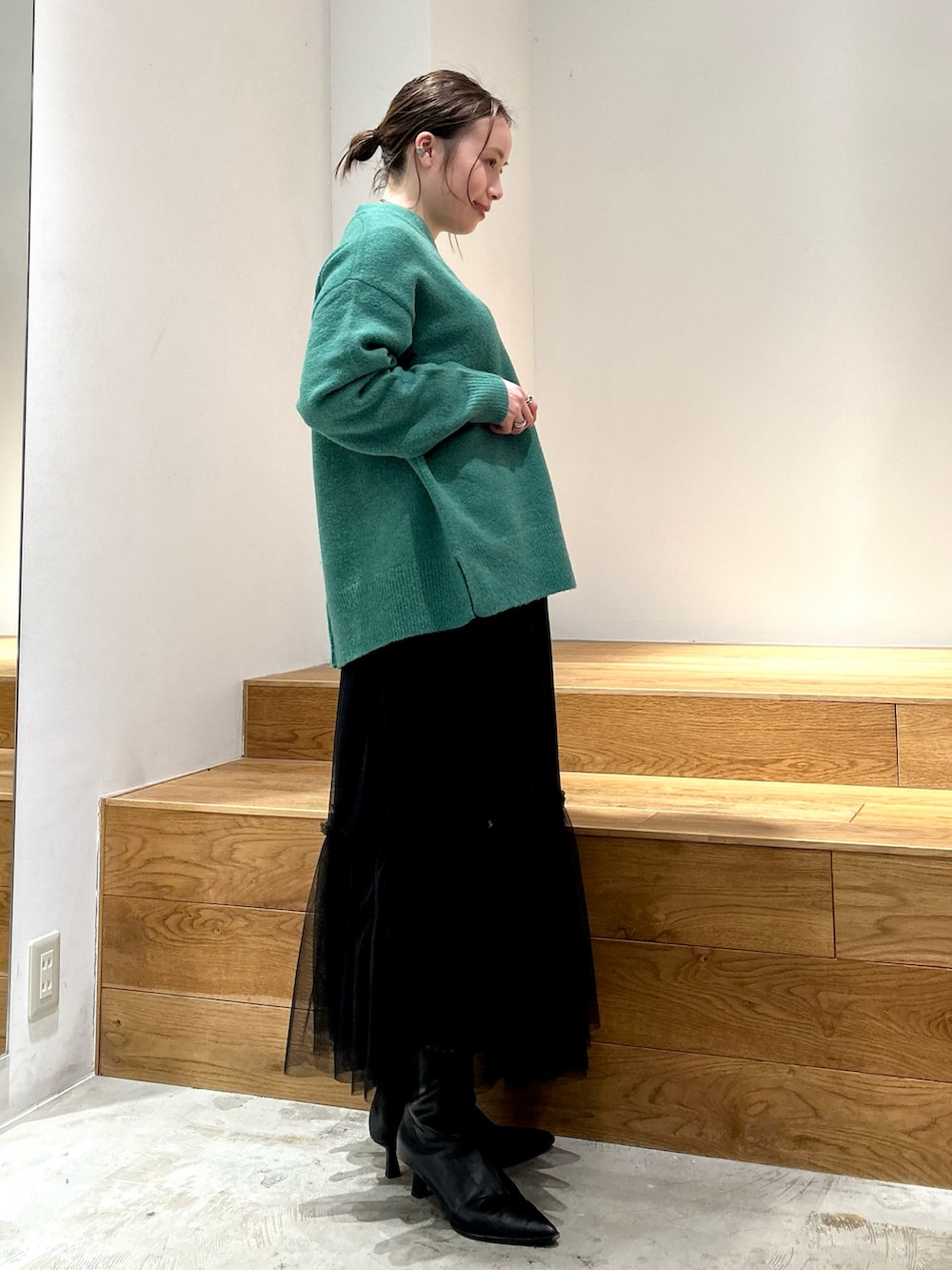 グリーン系のニット/セーター、ホワイト系のTシャツ/カットソー、ブラック系のスカートを着用したレディースの冬コーディネートの2枚目の写真