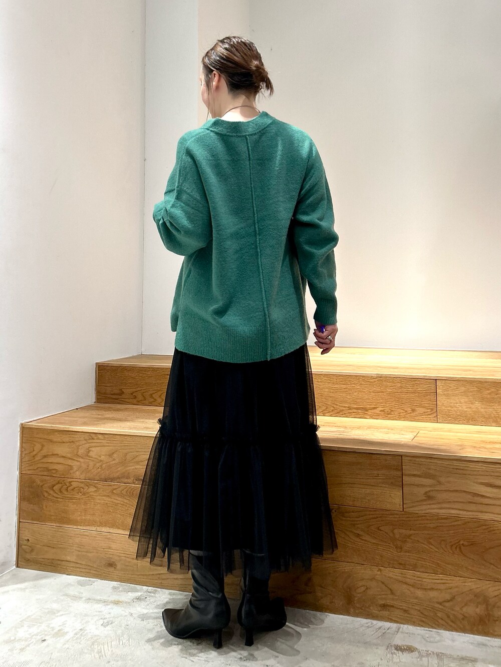 グリーン系のニット/セーター、ホワイト系のTシャツ/カットソー、ブラック系のスカートを着用したレディースの冬コーディネートの3枚目の写真