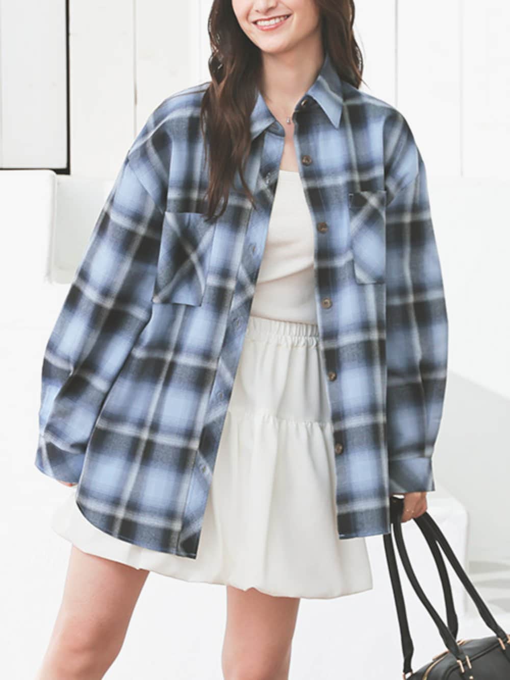 ブラック系のボストンバッグ、ホワイト系のスカート、ブルー系のシャツ/ブラウスを着用したレディースの秋コーディネートの3枚目の写真