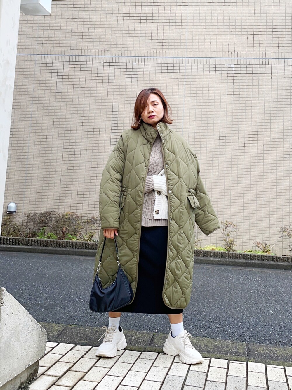 ブラック系のスカート、ホワイト系のカーディガン/ボレロ、ホワイト系のスニーカーを着用したレディースの冬コーディネートの2枚目の写真