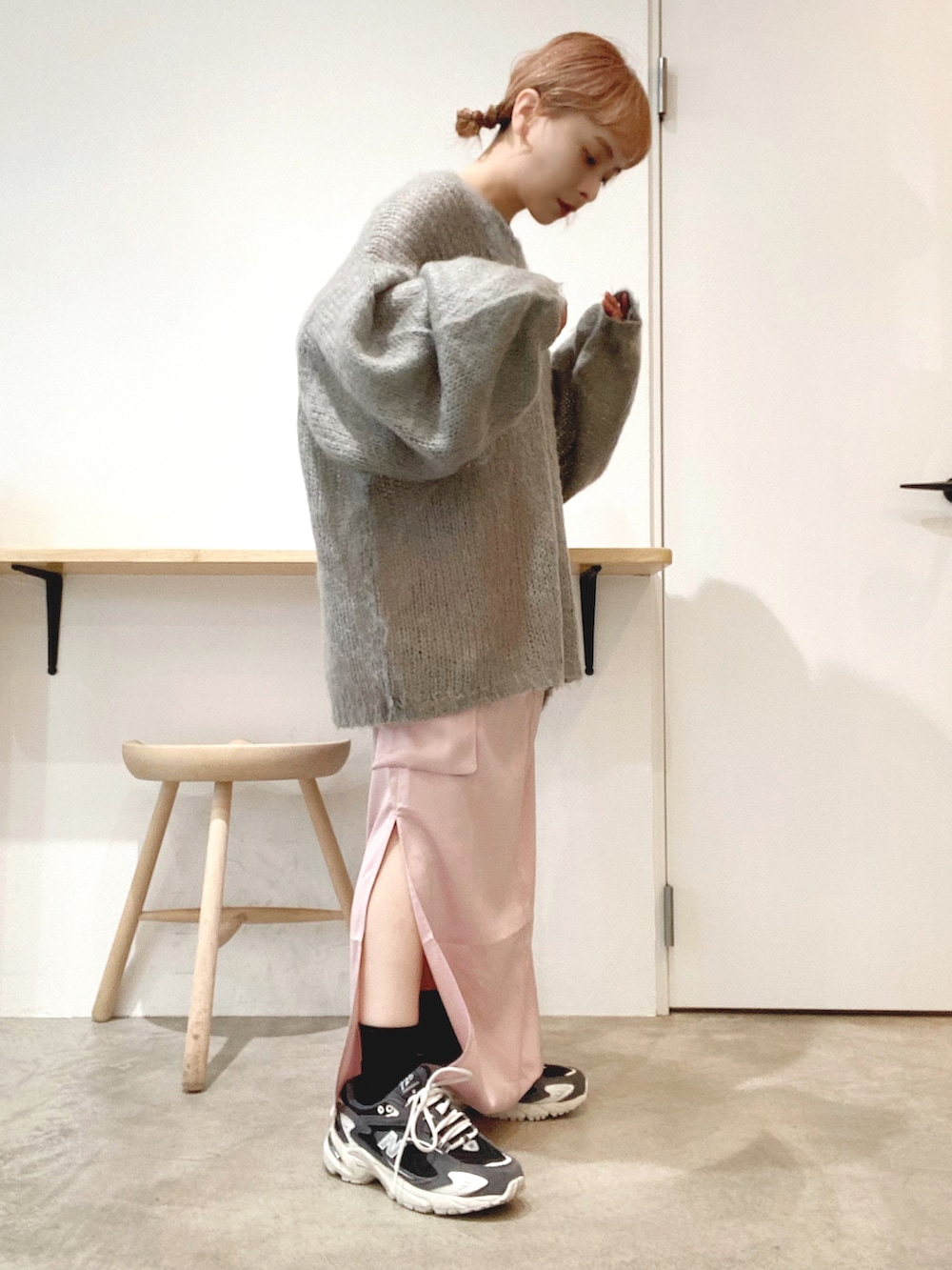 ブラック系のスニーカー、ピンク系のスカート、グレー系のニット/セーターを着用したレディースの秋コーディネートの2枚目の写真