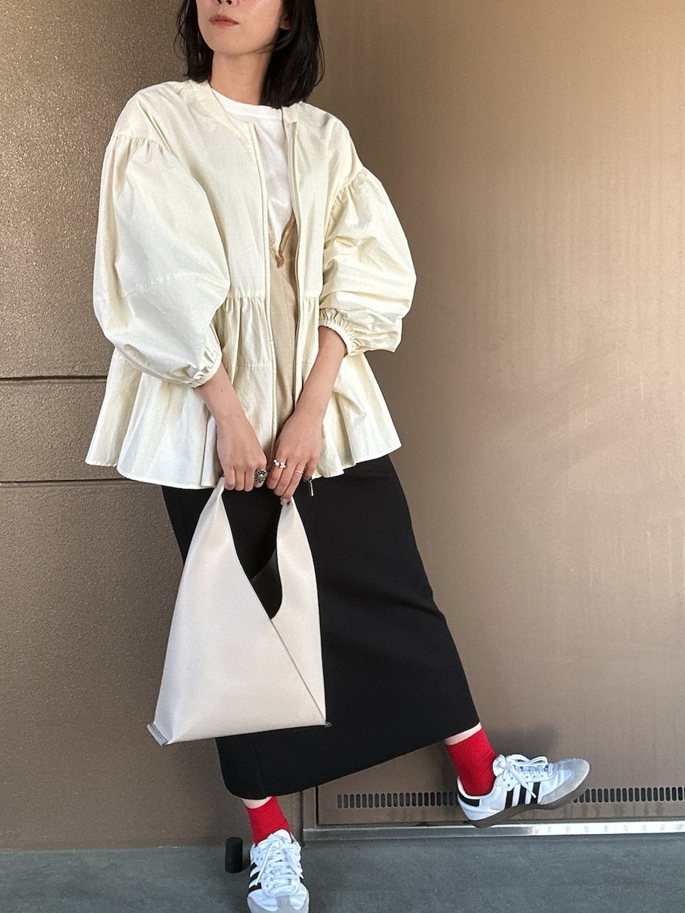 ホワイト系のスニーカー、ブラック系のスカート、ホワイト系のハンドバッグを着用したレディースの春コーディネートの2枚目の写真