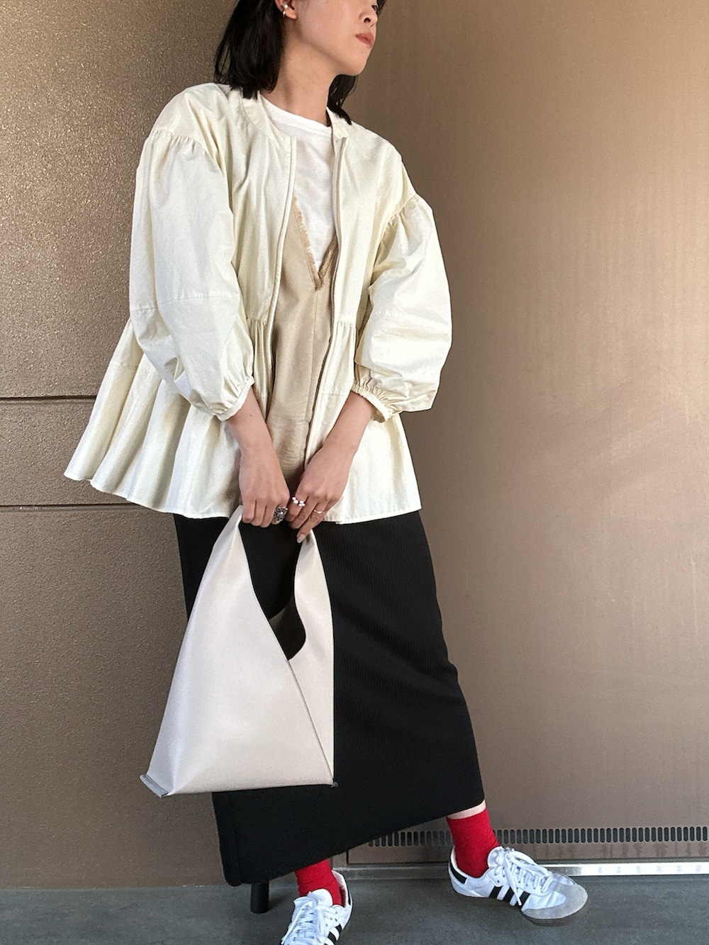 ホワイト系のスニーカー、ブラック系のスカート、ホワイト系のハンドバッグを着用したレディースの春コーディネートの3枚目の写真