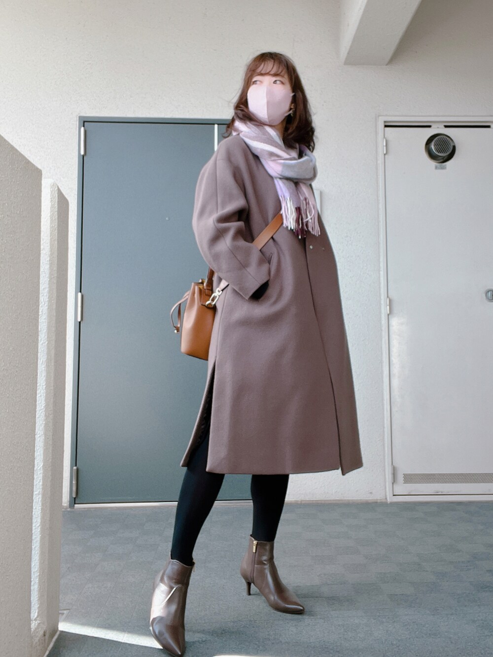 ブラウン系のブーツ、ブラック系のワンピース、ブラウン系のノーカラーコートを着用したレディースの冬コーディネートの2枚目の写真