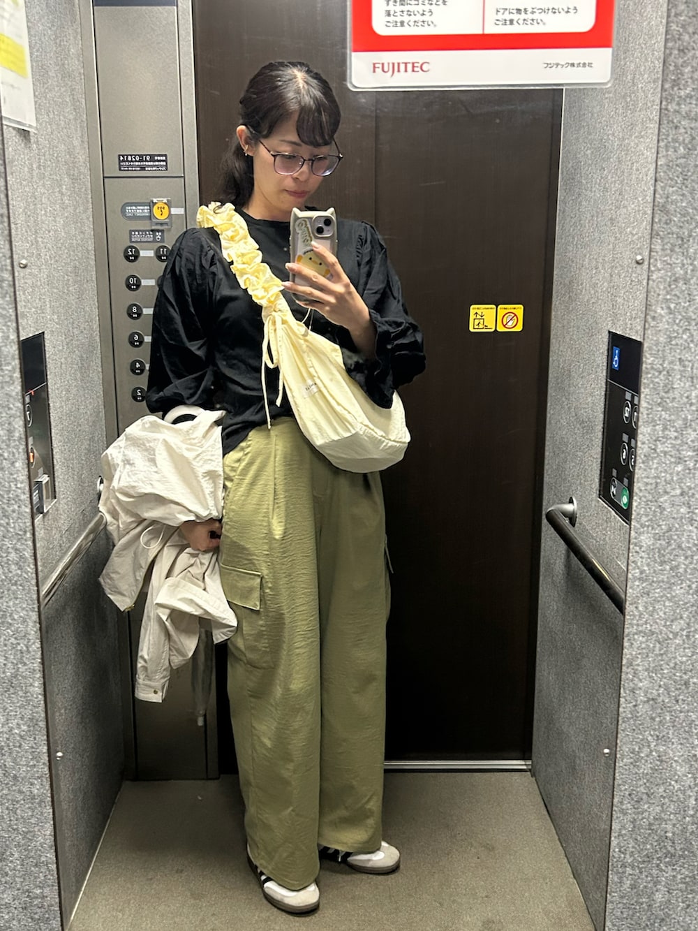 ホワイト系のスニーカー、グリーン系のカーゴパンツ、ホワイト系のブルゾンを着用したレディースの春コーディネートの4枚目の写真