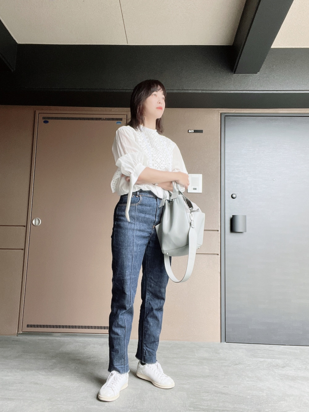 ホワイト系のスニーカー、ブルー系のデニムパンツ、グレー系のショルダーバッグを着用したレディースの秋コーディネートの2枚目の写真