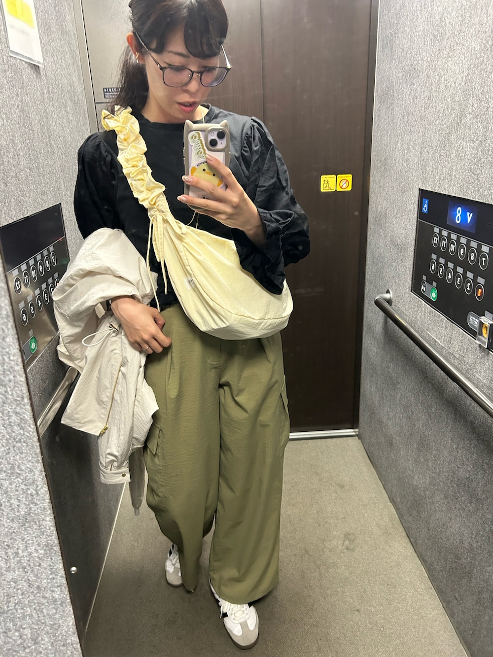 ホワイト系のスニーカー、グリーン系のカーゴパンツ、ホワイト系のブルゾンを着用したレディースの春コーディネートの3枚目の写真