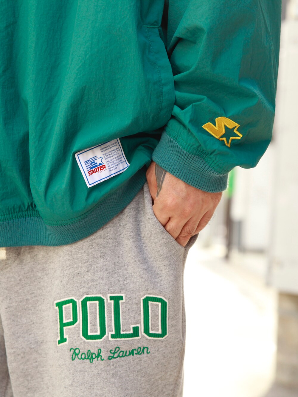 グリーン系のナイロンジャケット、グレー系のスウェットパンツ、ホワイト系のスニーカーを着用したメンズの秋コーディネートの4枚目の写真