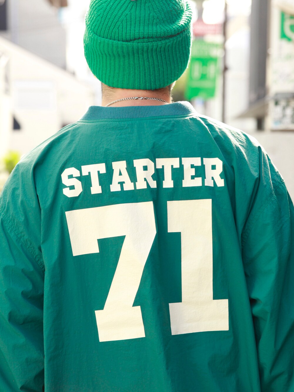 グリーン系のナイロンジャケット、グレー系のスウェットパンツ、ホワイト系のスニーカーを着用したメンズの秋コーディネートの5枚目の写真