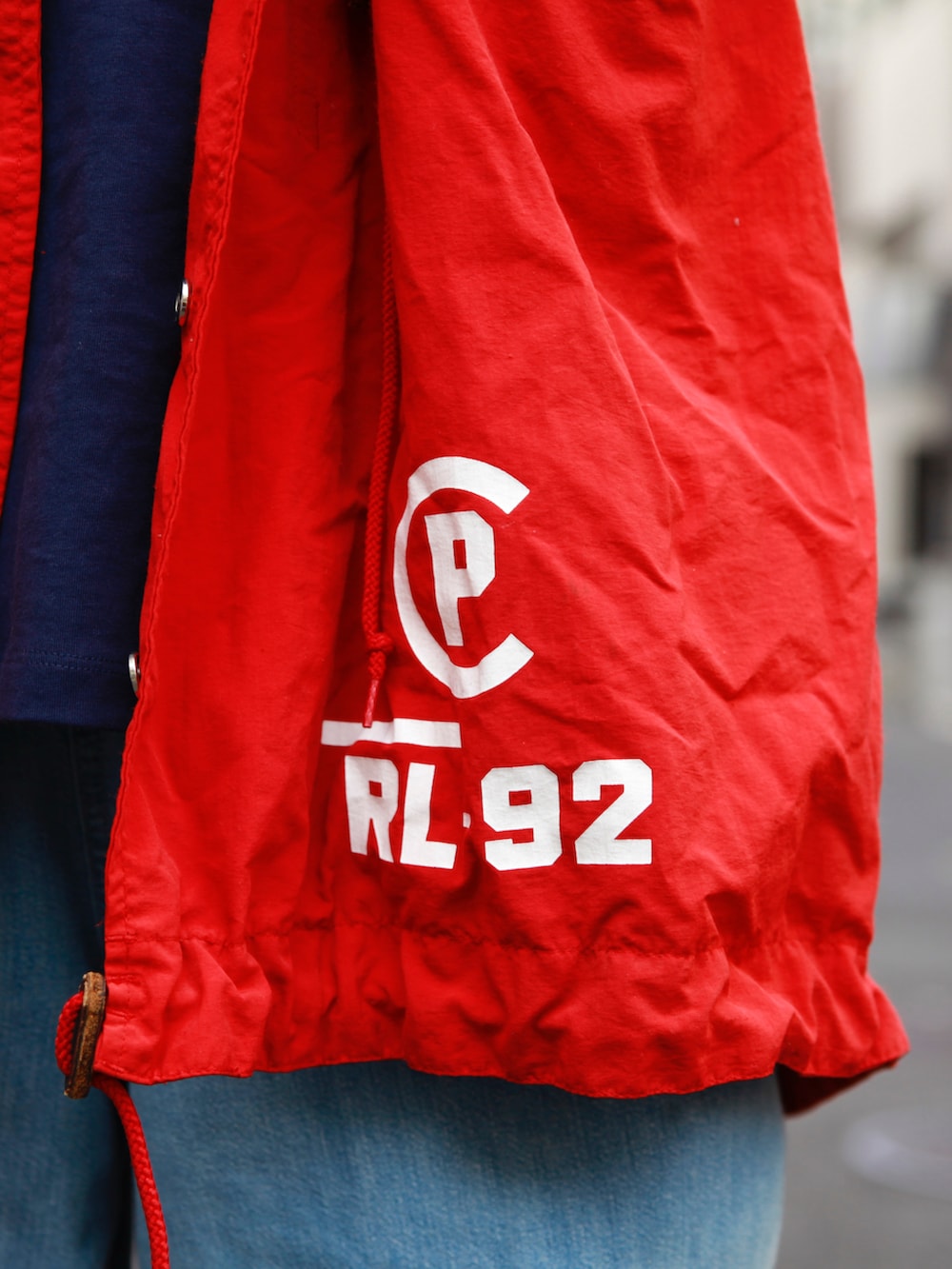 ブルー系のTシャツ/カットソー、レッド系のモッズコート、ブルー系のデニムパンツを着用したメンズの春コーディネートの4枚目の写真