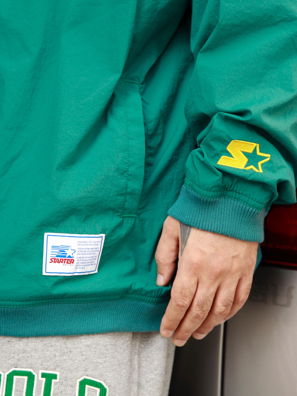 グリーン系のナイロンジャケット、グレー系のスウェットパンツ、ホワイト系のスニーカーを着用したメンズの秋コーディネートの2枚目の写真