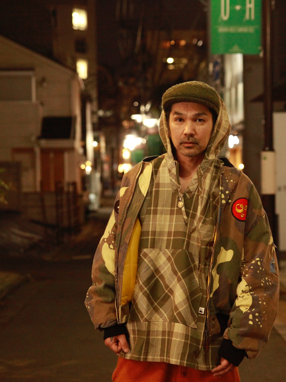 グリーン系のMA-1、ベージュ系のシャツ/ブラウス、オレンジ系のスウェットパンツを着用したメンズの春コーディネートの2枚目の写真