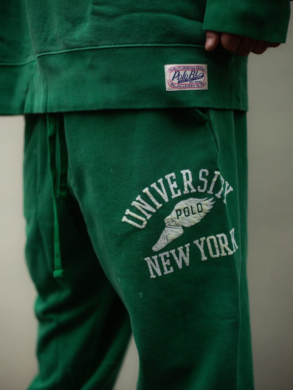 グリーン系のスウェット、グリーン系のスウェットパンツ、ブラウン系のスニーカーを着用したメンズの夏コーディネートの3枚目の写真