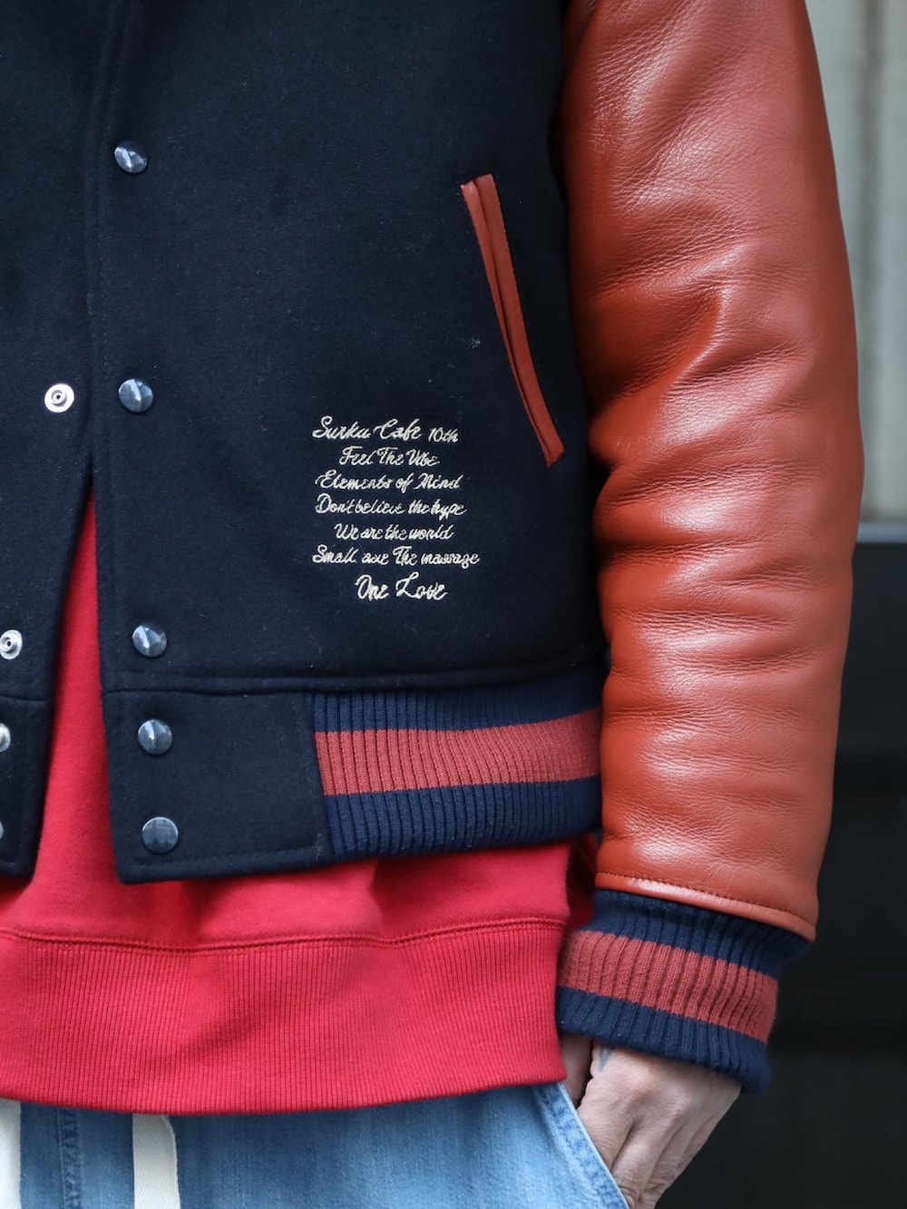 ブルー系のスタジャン、レッド系のスウェット、ブルー系のデニムパンツを着用したメンズの冬コーディネートの2枚目の写真