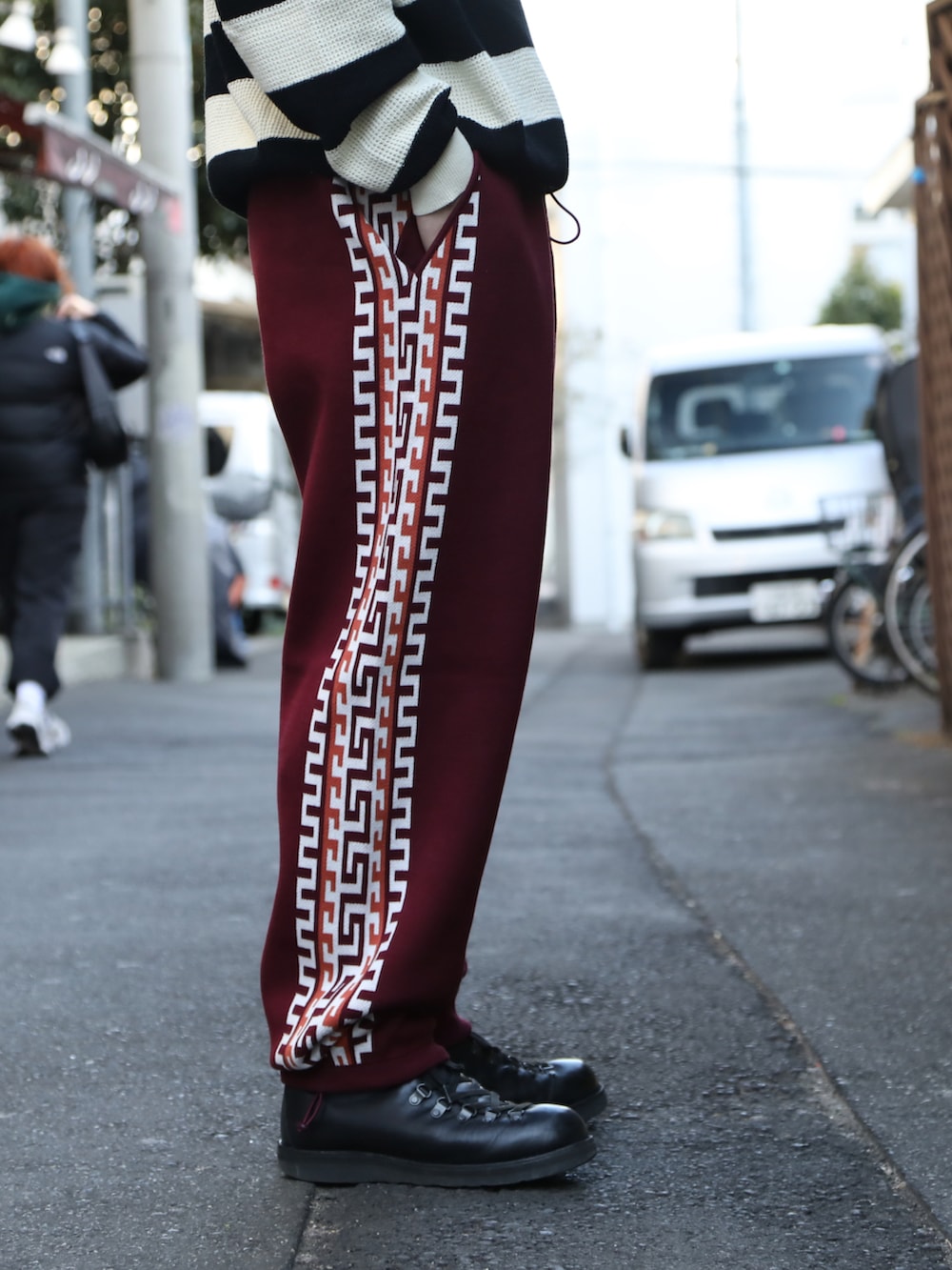 ホワイト系のニット/セーター、レッド系のパンツ、ブラック系のブーツを着用したメンズの春コーディネートの3枚目の写真