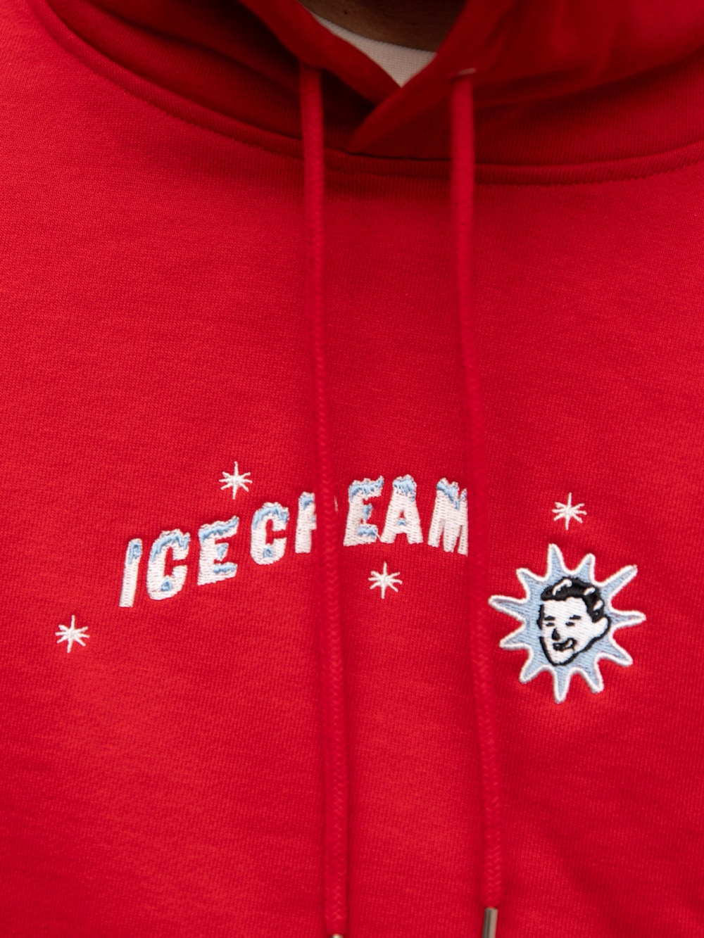 レッド系のパーカー、ホワイト系のTシャツ/カットソー、ブルー系のデニムパンツを着用したメンズの春コーディネートの2枚目の写真