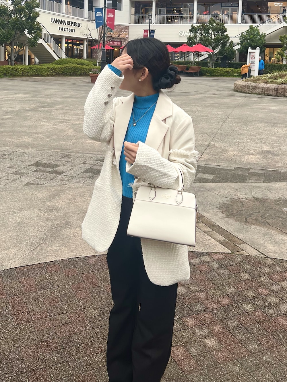 ホワイト系のテーラードジャケット、ブラック系のブーツ、ブルー系のニット/セーターを着用したレディースの冬コーディネートの2枚目の写真