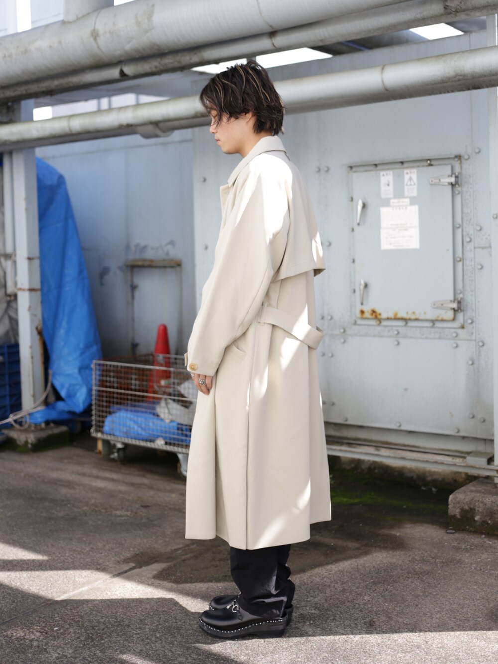 ベージュ系のステンカラーコート、ブラック系のスラックスを着用したメンズの秋コーディネートの3枚目の写真