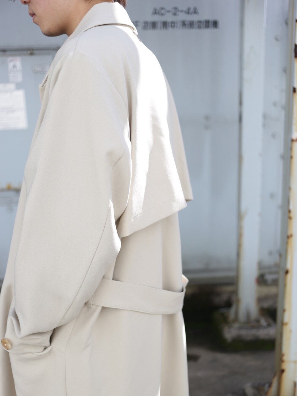 ベージュ系のステンカラーコート、ブラック系のスラックスを着用したメンズの秋コーディネートの5枚目の写真