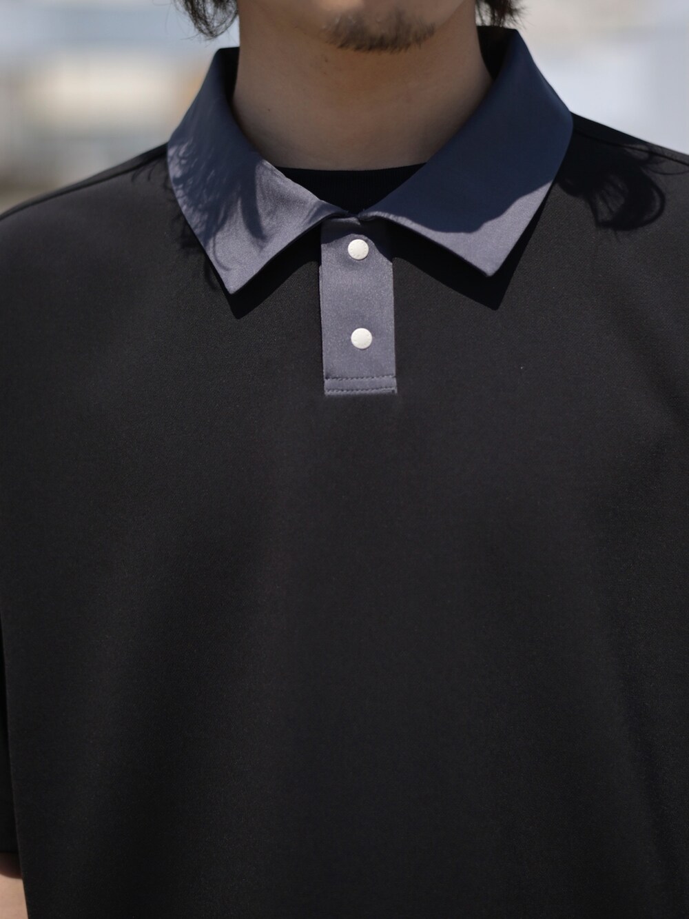 ブラック系のポロシャツを着用したメンズの春コーディネートの5枚目の写真