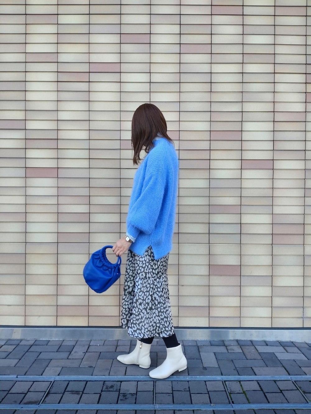 ブルー系のニット/セーター、ホワイト系のブーツ、グリーン系のスカートを着用したレディースの冬コーディネートの4枚目の写真