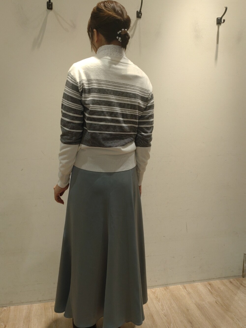 グリーン系のスカート、ホワイト系のカーディガン/ボレロ、ホワイト系のTシャツ/カットソーを着用したレディースの冬コーディネートの2枚目の写真