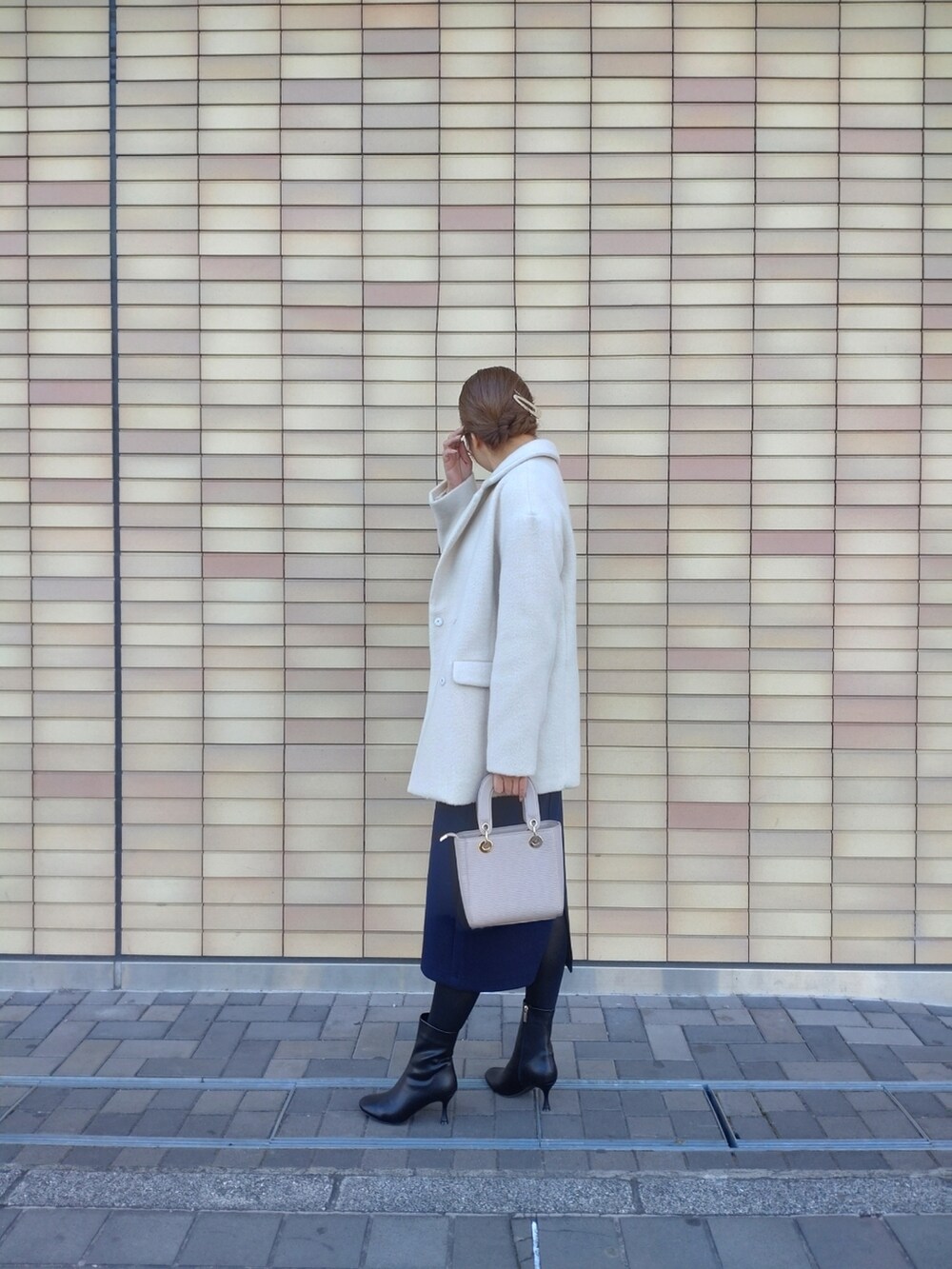 ベージュ系のハンドバッグ、ブラック系のブーツ、ブルー系のジャンパースカートを着用したレディースの冬コーディネートの4枚目の写真