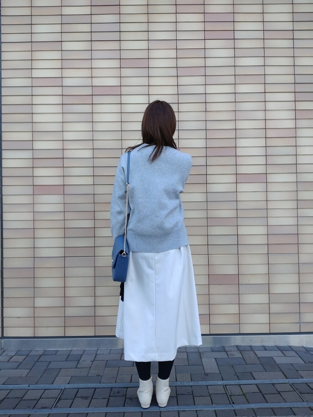 グレー系のニット/セーター、ホワイト系のスカート、ホワイト系のブーツを着用したレディースの冬コーディネートの4枚目の写真