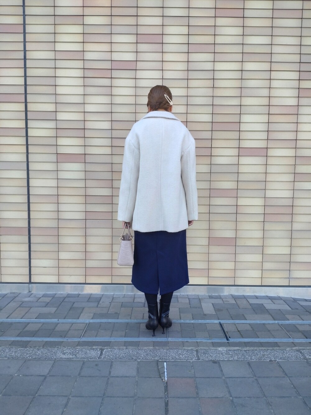 ベージュ系のハンドバッグ、ブラック系のブーツ、ブルー系のジャンパースカートを着用したレディースの冬コーディネートの3枚目の写真