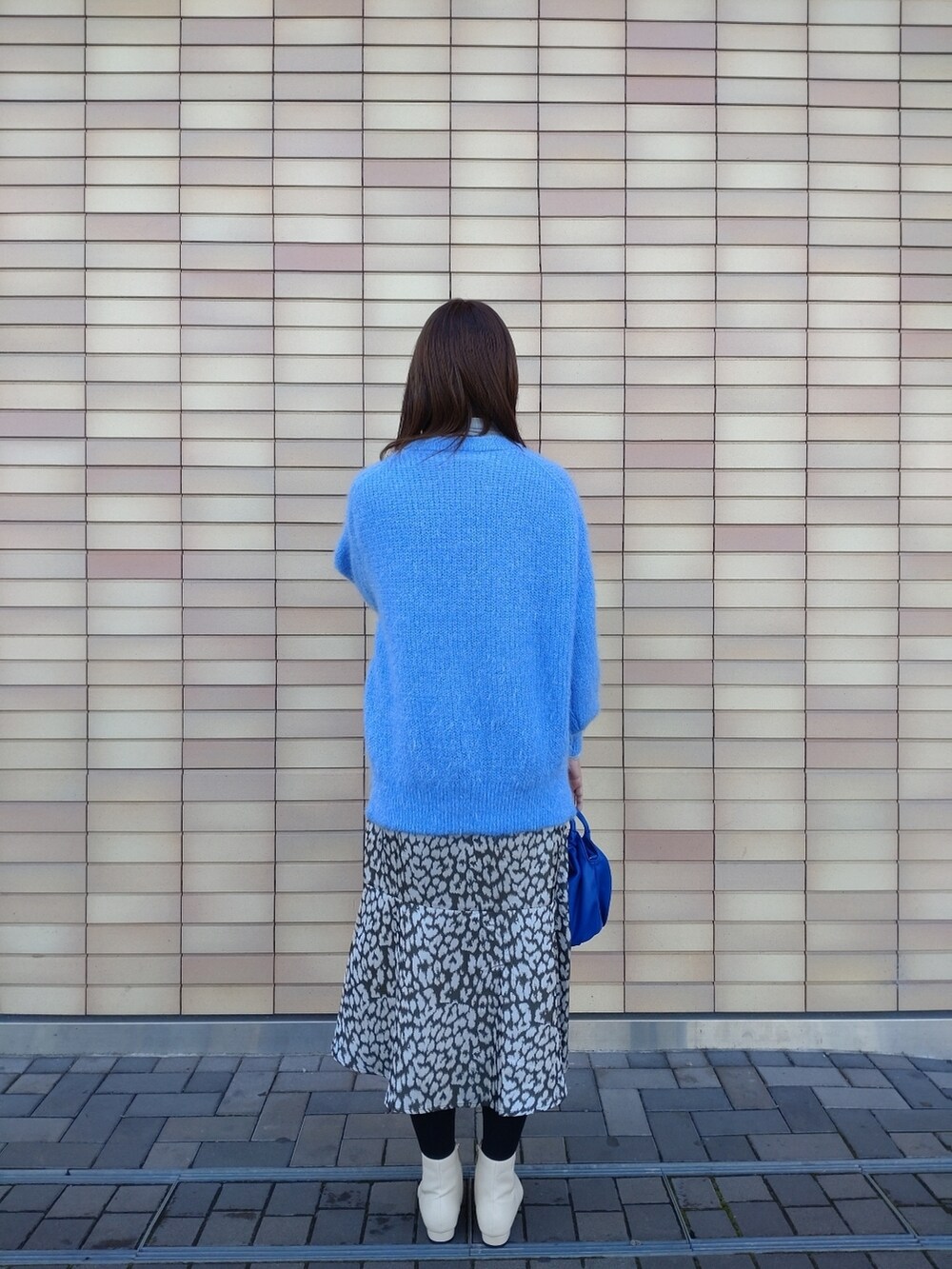 ブルー系のニット/セーター、ホワイト系のブーツ、グリーン系のスカートを着用したレディースの冬コーディネートの3枚目の写真