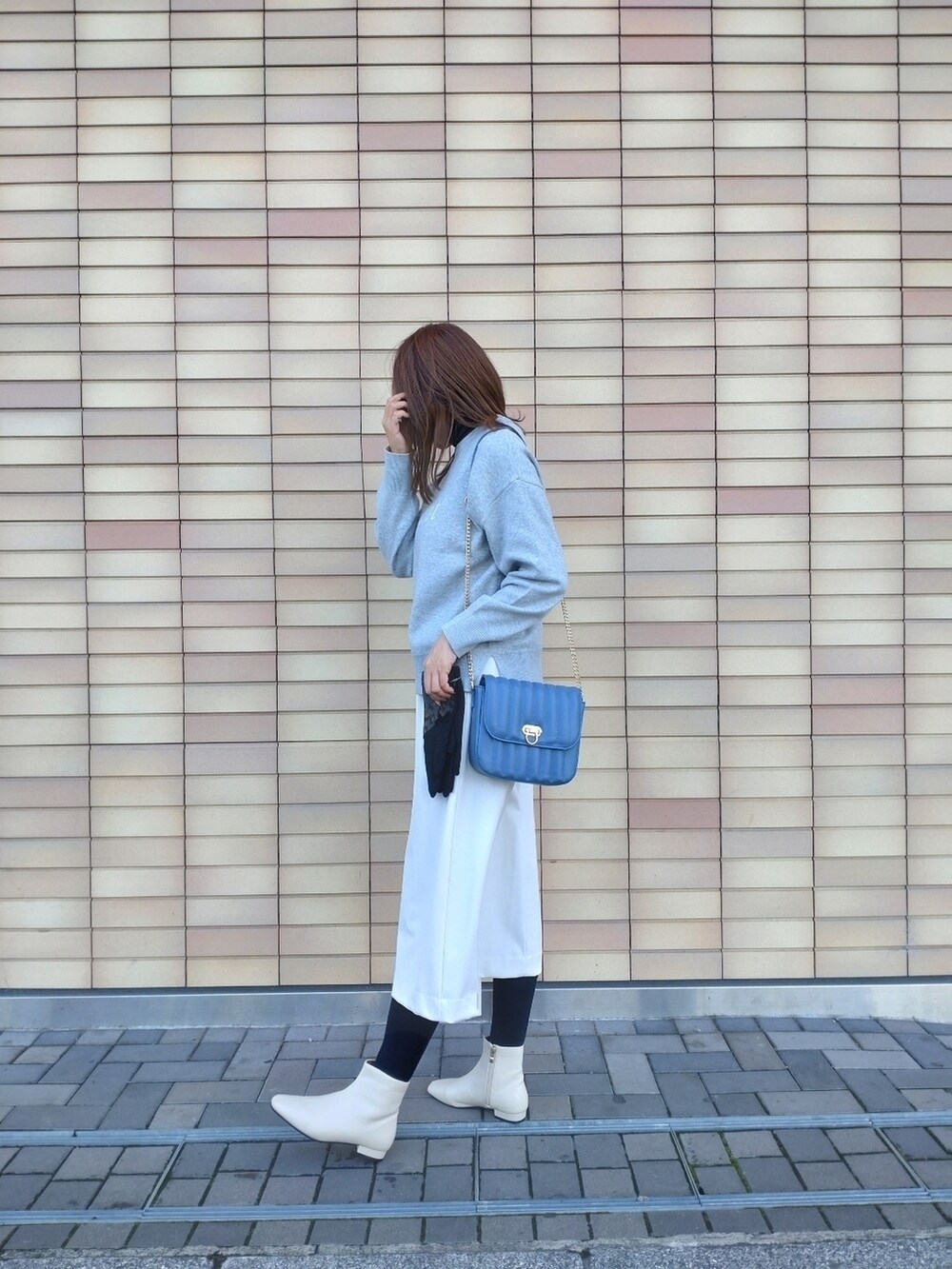 グレー系のニット/セーター、ホワイト系のスカート、ホワイト系のブーツを着用したレディースの冬コーディネートの3枚目の写真