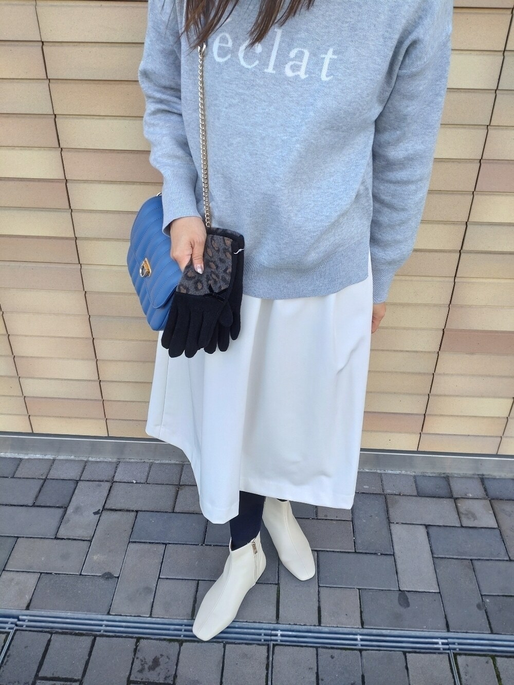 グレー系のニット/セーター、ホワイト系のスカート、ホワイト系のブーツを着用したレディースの冬コーディネートの5枚目の写真