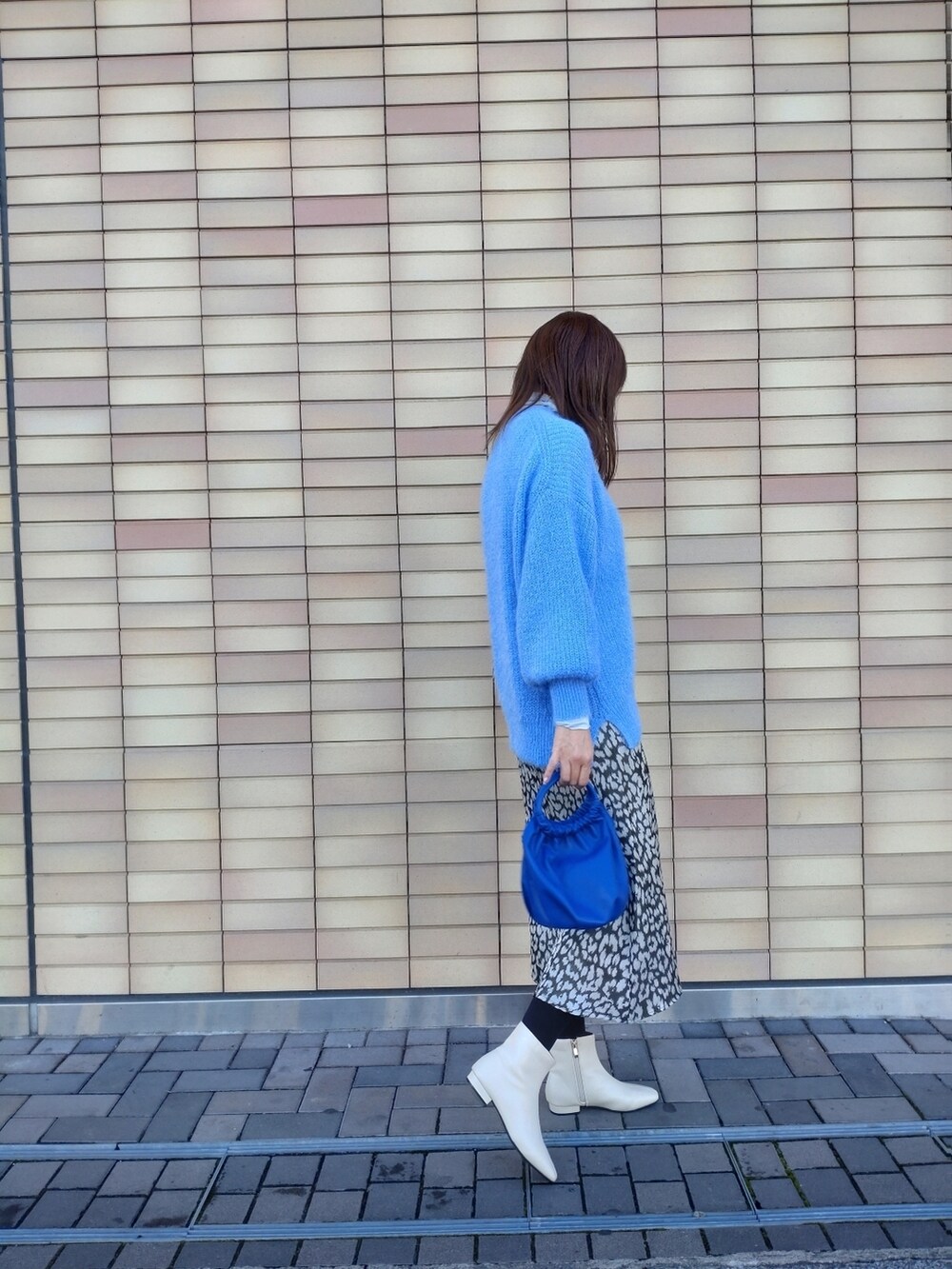 ブルー系のニット/セーター、ホワイト系のブーツ、グリーン系のスカートを着用したレディースの冬コーディネートの2枚目の写真