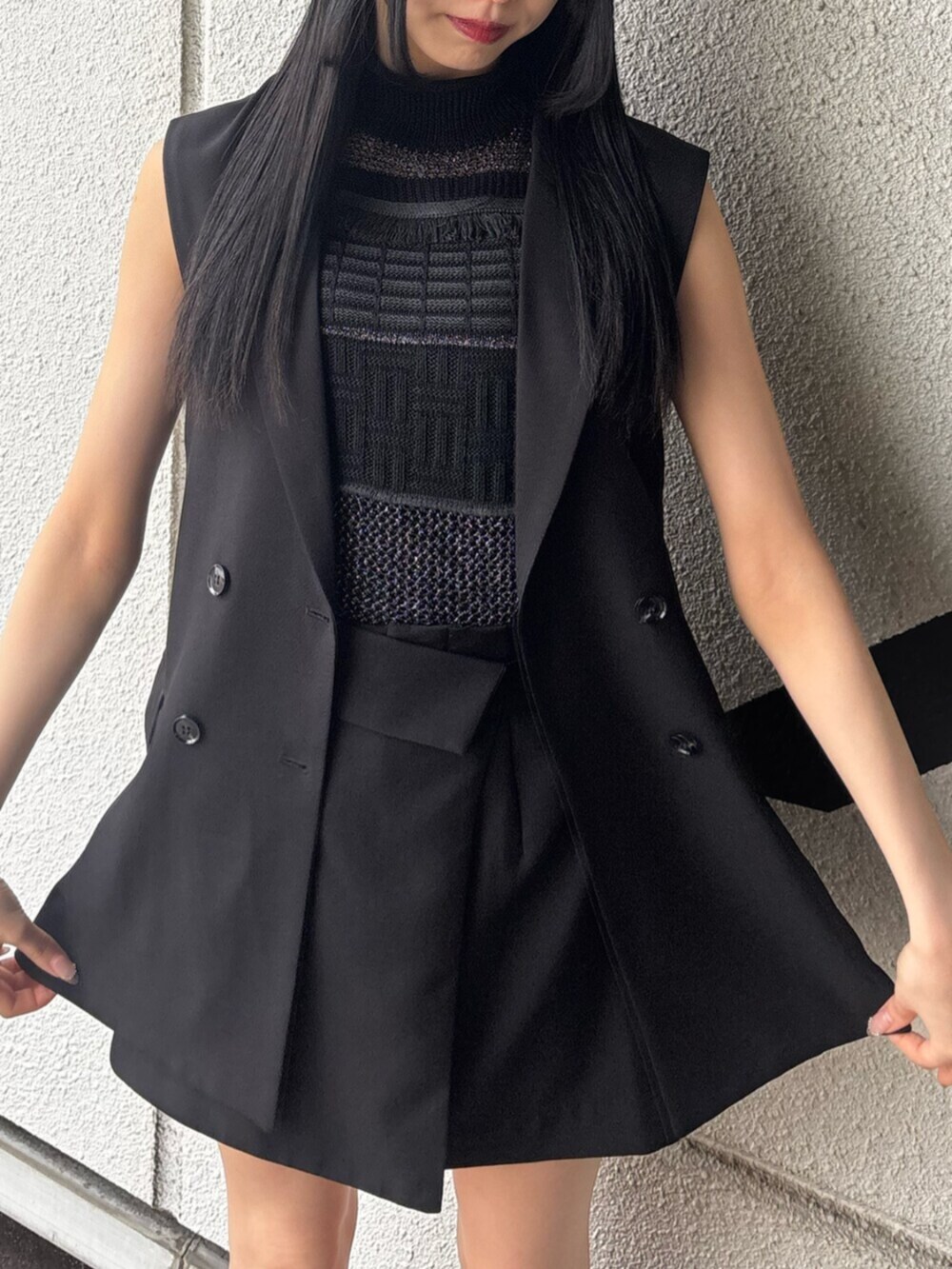 ブラック系のスカート、ブラック系のタンクトップ、ブラック系のベストを着用したレディースの春コーディネートの6枚目の写真