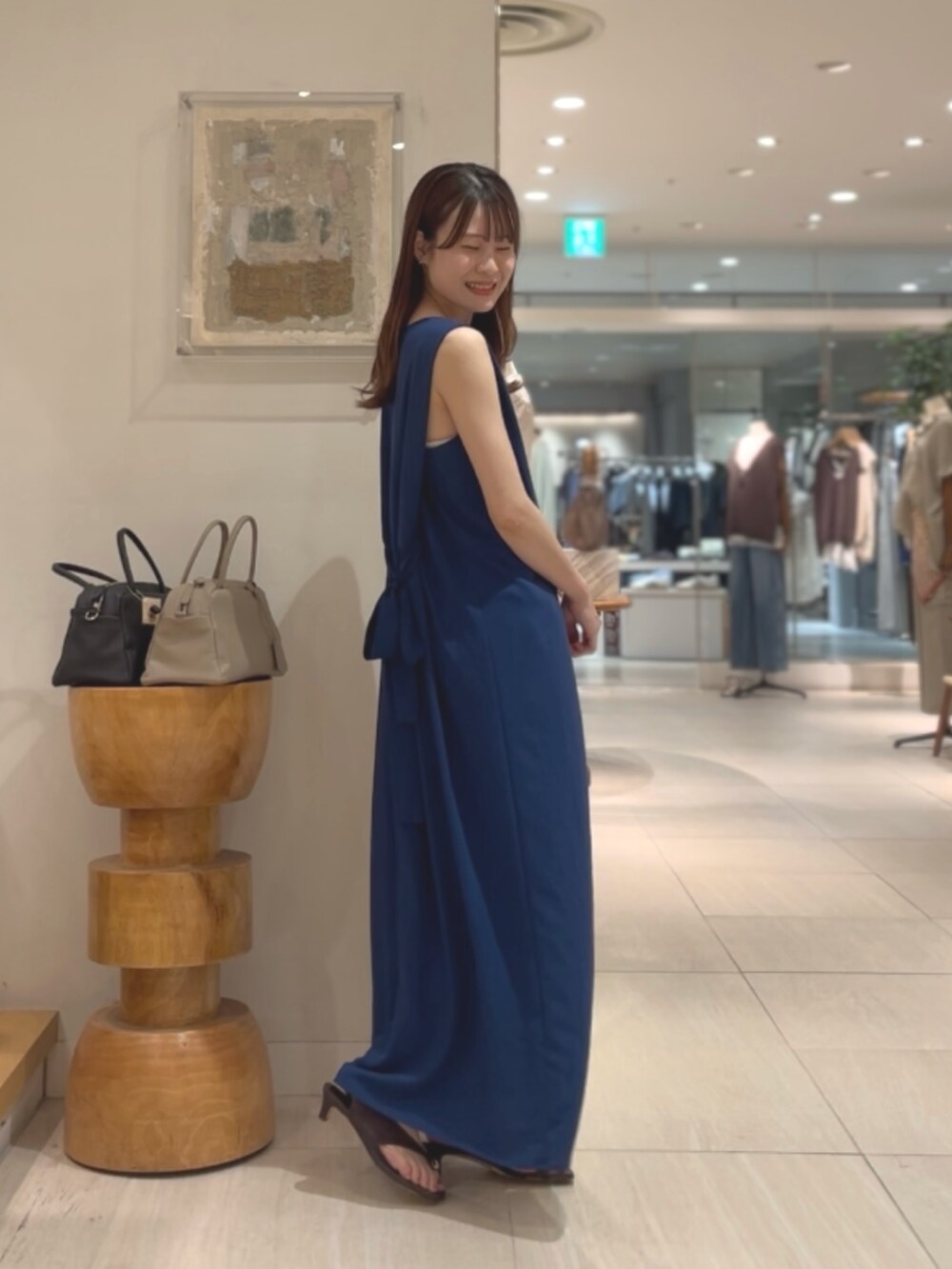 ブルー系のワンピース、ブラウン系のサンダル、シルバー系のネックレスを着用したレディースの夏コーディネートの2枚目の写真