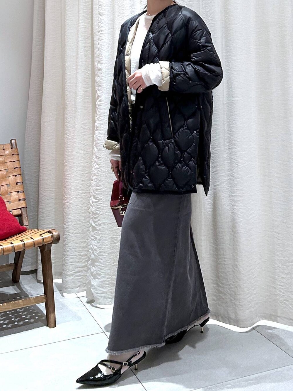 ブラック系のダウンジャケット/コート、グレー系のスカート、ホワイト系のニット/セーターを着用したレディースの秋コーディネートの4枚目の写真