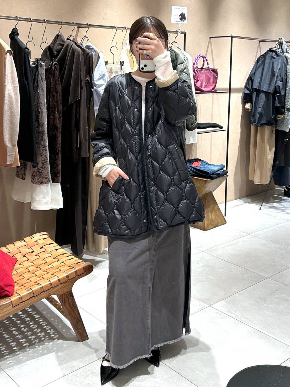 ブラック系のダウンジャケット/コート、グレー系のスカート、ホワイト系のニット/セーターを着用したレディースの秋コーディネートの2枚目の写真