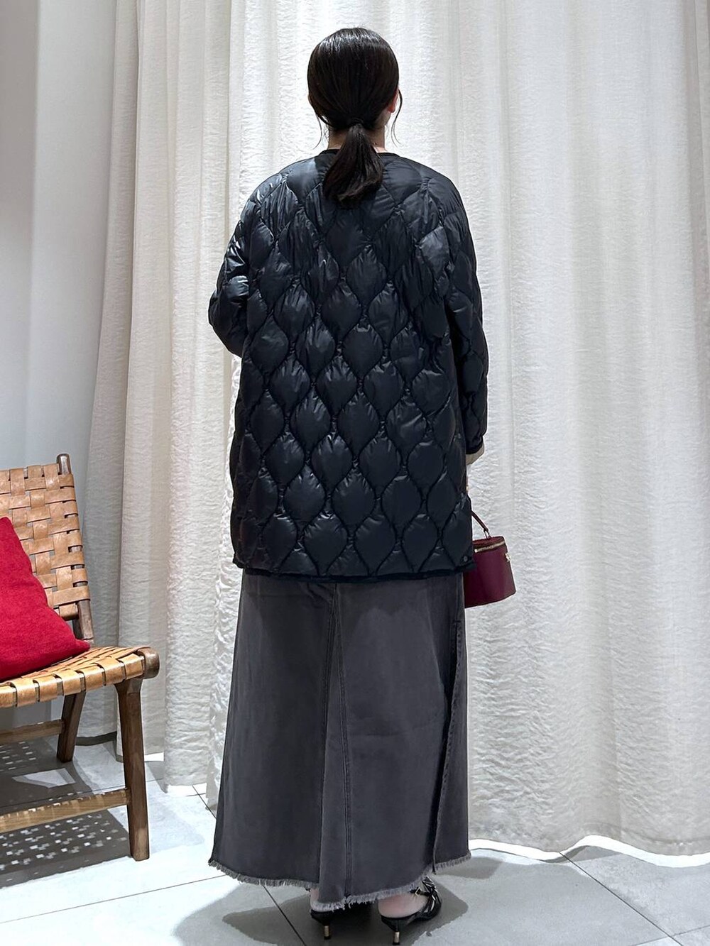 ブラック系のダウンジャケット/コート、グレー系のスカート、ホワイト系のニット/セーターを着用したレディースの秋コーディネートの5枚目の写真