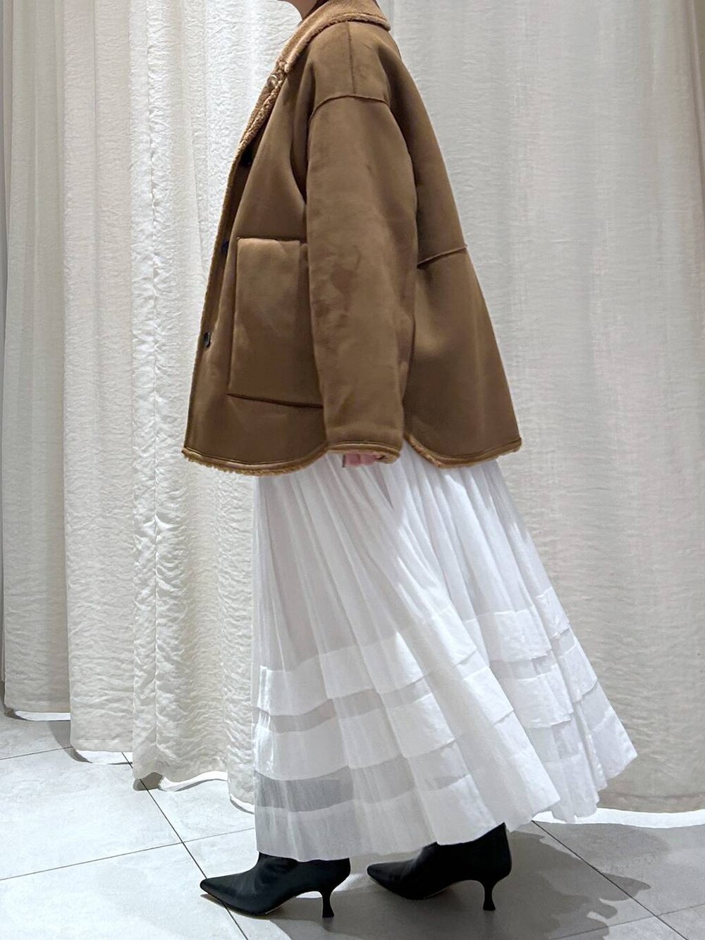 ホワイト系のニット/セーター、ホワイト系のスカート、イエロー系のブルゾンを着用したレディースの秋コーディネートの3枚目の写真