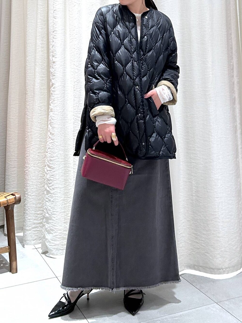 ブラック系のダウンジャケット/コート、グレー系のスカート、ホワイト系のニット/セーターを着用したレディースの秋コーディネートの3枚目の写真