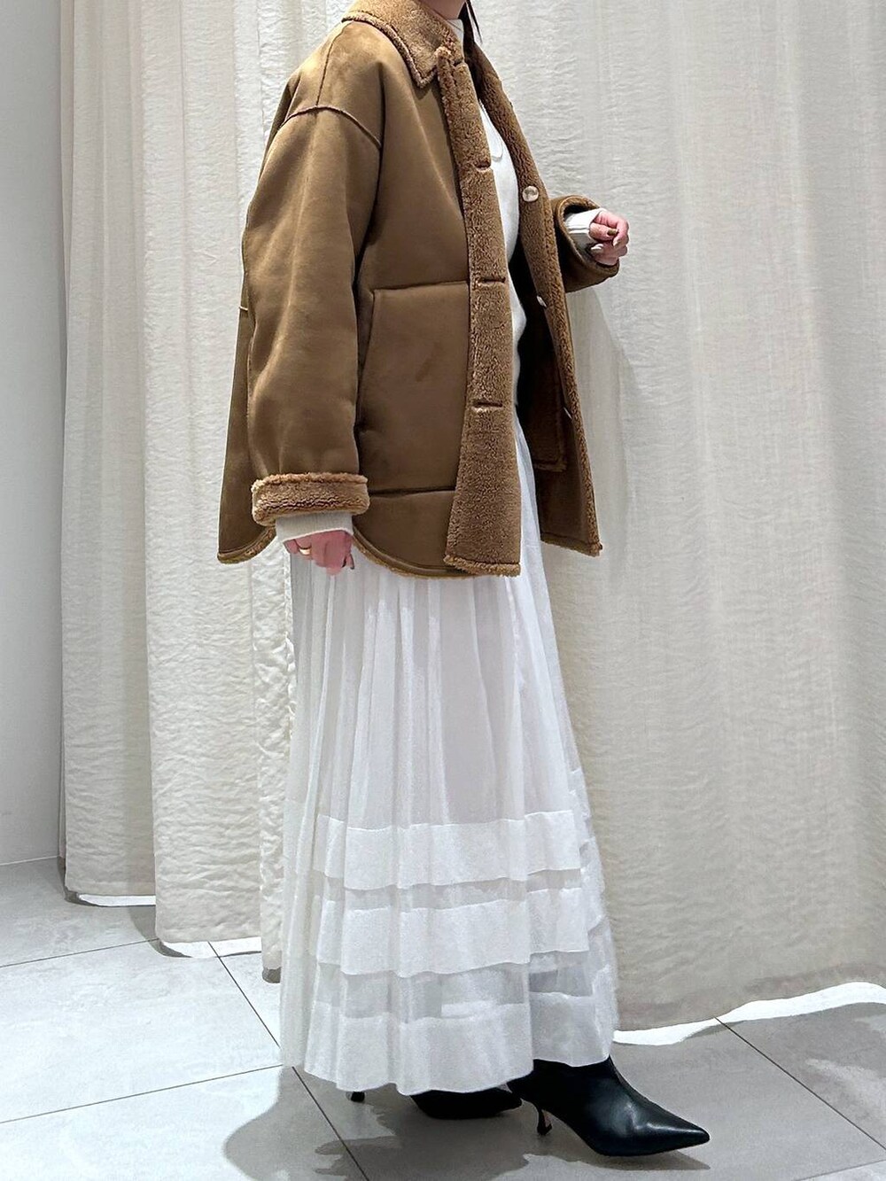 ホワイト系のニット/セーター、ホワイト系のスカート、イエロー系のブルゾンを着用したレディースの秋コーディネートの6枚目の写真