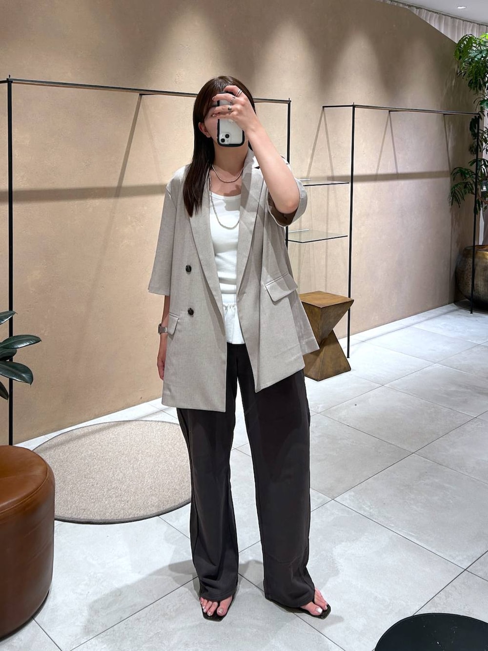 ベージュ系のテーラードジャケット、グレー系のスウェットパンツ、ホワイト系のタンクトップを着用したレディースの夏コーディネートの2枚目の写真