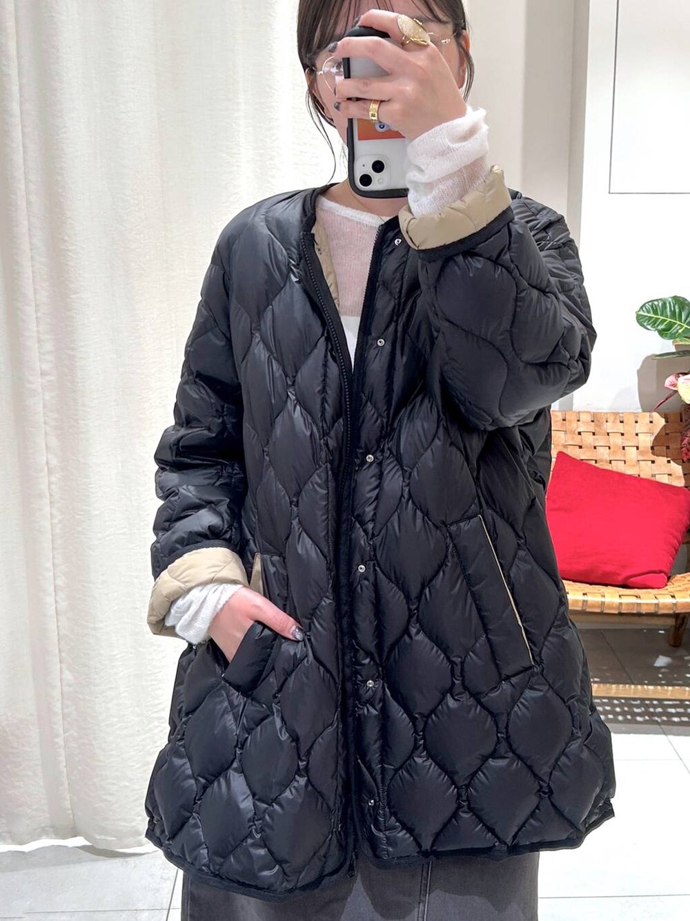 ブラック系のダウンジャケット/コート、グレー系のスカート、ホワイト系のニット/セーターを着用したレディースの秋コーディネートの8枚目の写真