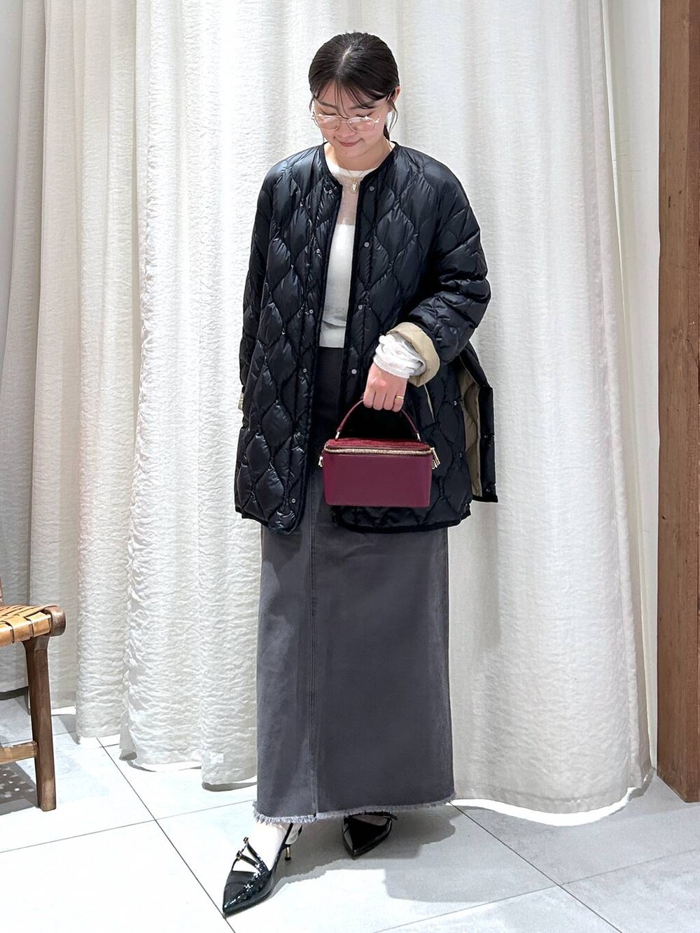 ブラック系のダウンジャケット/コート、グレー系のスカート、ホワイト系のニット/セーターを着用したレディースの秋コーディネートの7枚目の写真