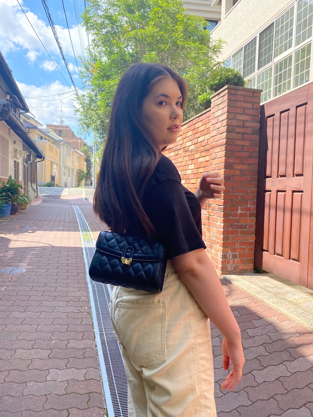 ブラック系のショルダーバッグ、ブラック系のTシャツ/カットソー、ベージュ系のその他パンツを着用したレディースの冬コーディネートの2枚目の写真